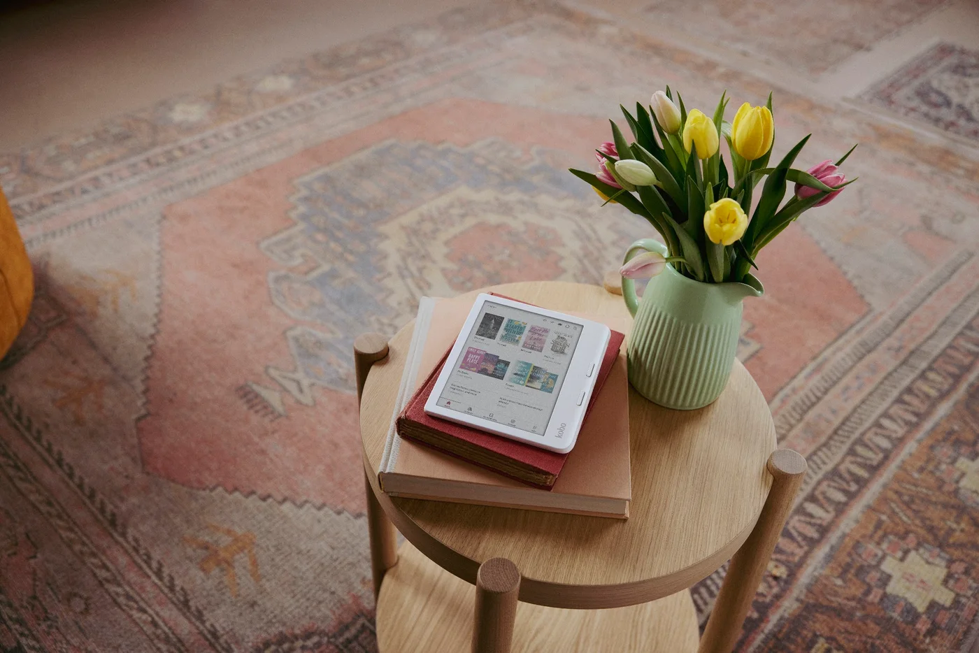 Kobo Libra Colour posée sur des livres près d’un vase de tulipes